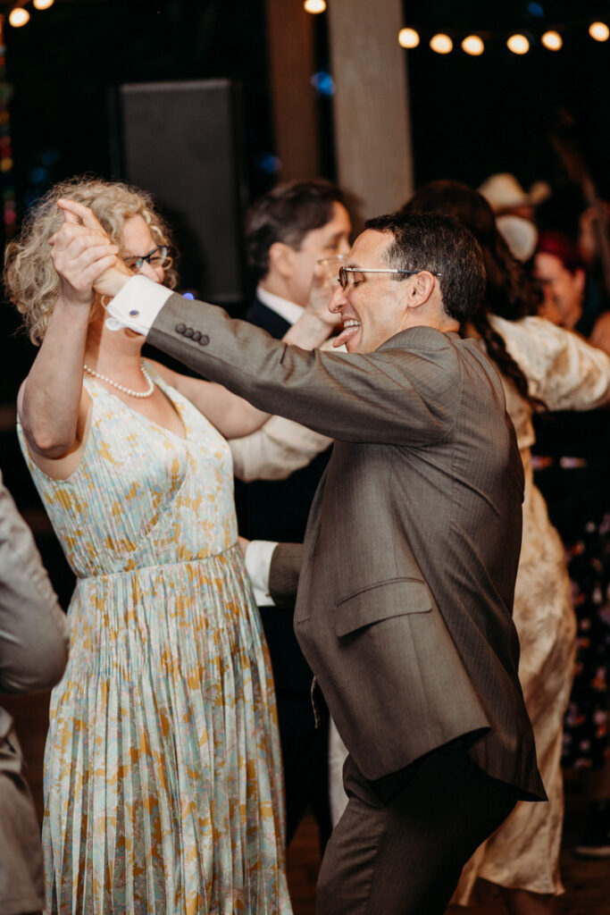 Man in suit and woman in floral dress dancing at wedding reception 