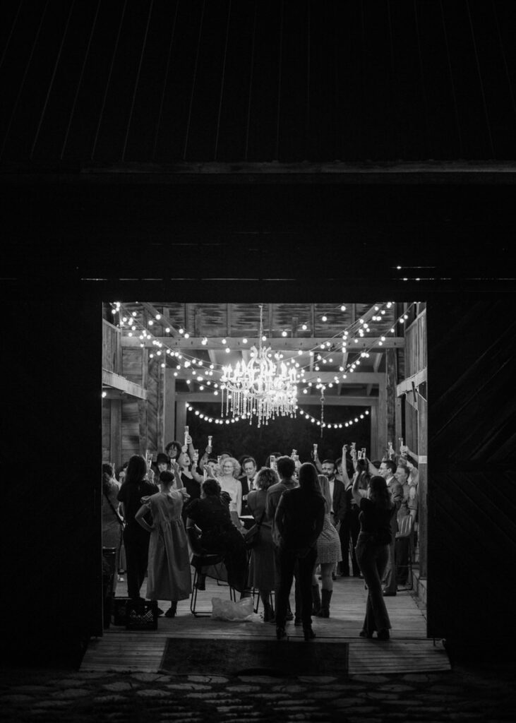 Black and white photo of wedding reception with chandelier and string lights