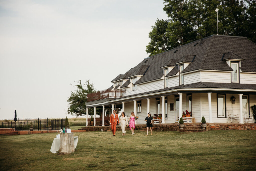 A well-dressed group walking in front of a historic house with a wide porch, a classic Oklahoma City wedding venue setting