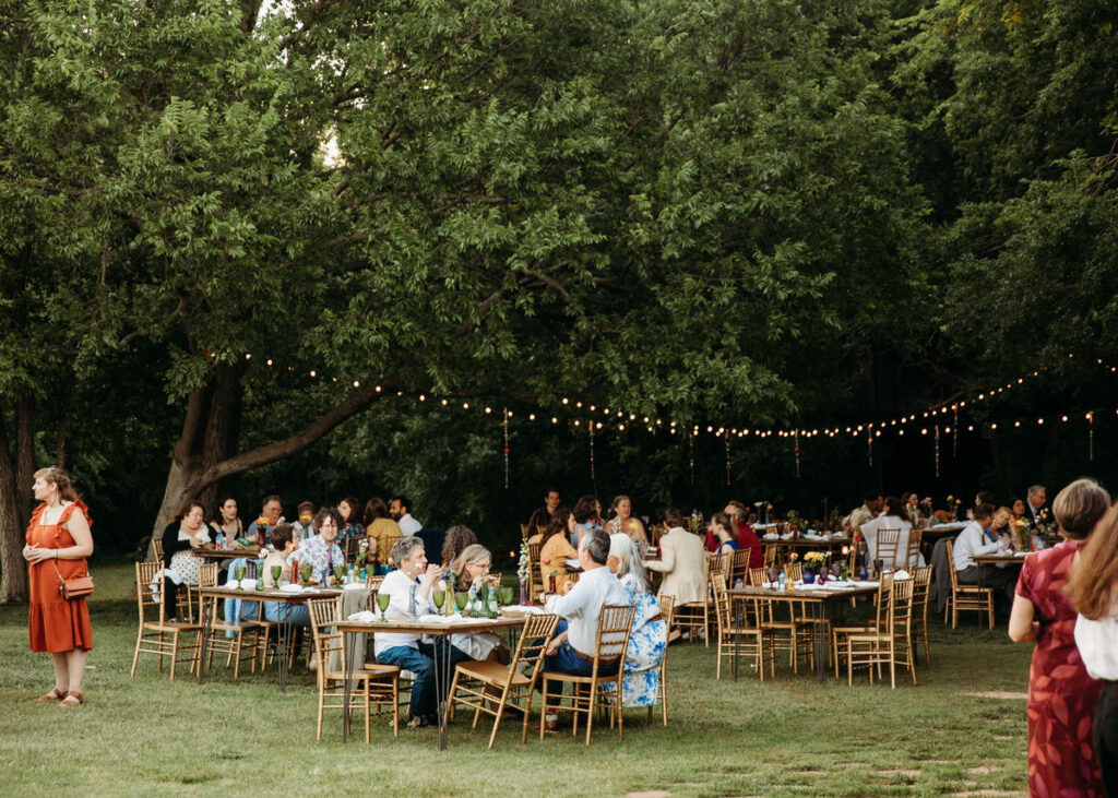 Guests enjoying an outdoor wedding reception under string lights at a green lawn in an Oklahoma City wedding venue