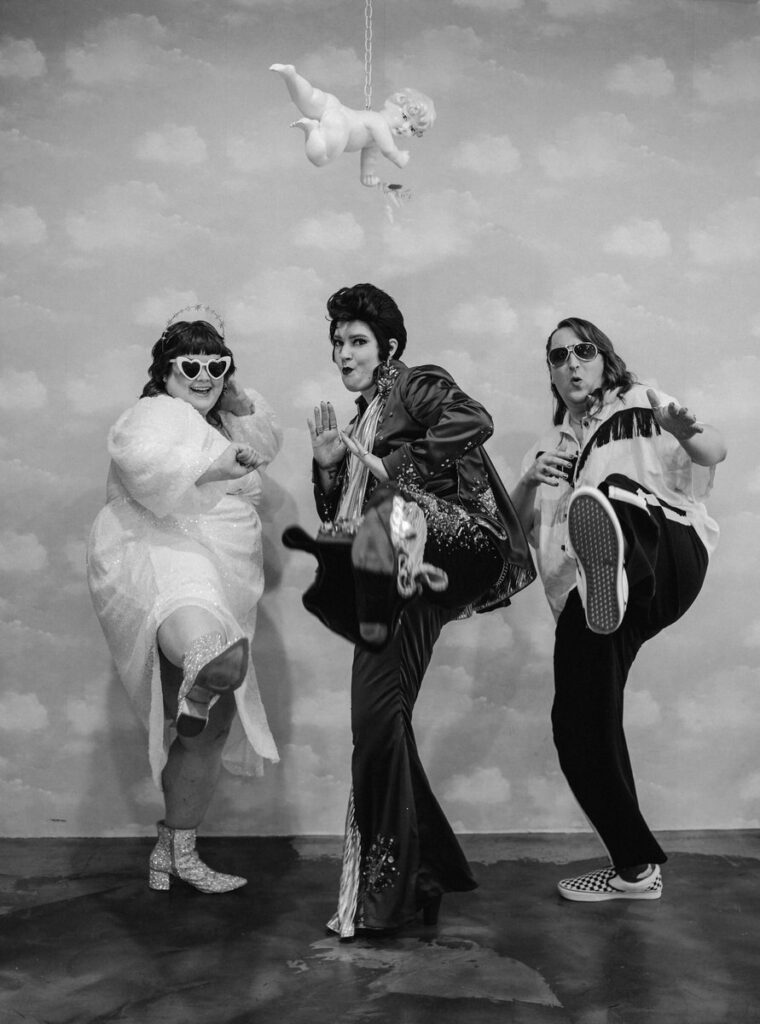A black and white photo featuring wedding guests in retro costumes with an Elvis impersonator, capturing a whimsical and theatrical Vegas-themed elopement