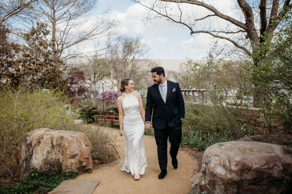 Newlyweds walking hand in hand through the Myriad Gardens, a popular Oklahoma City wedding venue with natural scenery