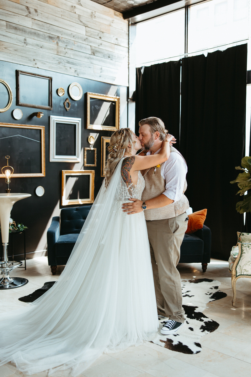 Bride and groom embracing in a stylish interior with eclectic decor, representing a unique Oklahoma City wedding venue