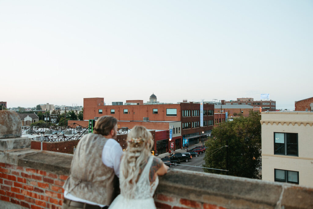 Bride and groom overlooking the cityscape from a rooftop, a charming Oklahoma City downtown wedding venue at dusk